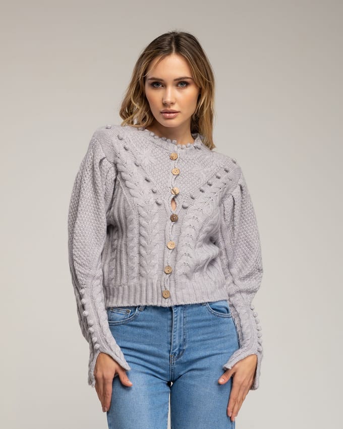 Gehaakt vest met pompons en bloemendetails.