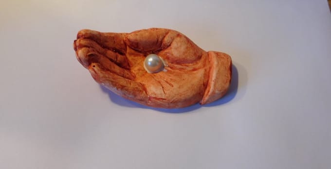 Beeld hand met parel bruin