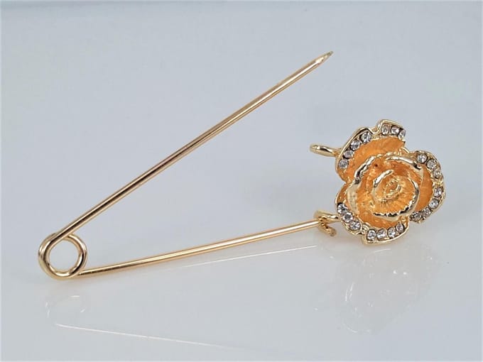Speld, goudkleur, roosje met strass steentjes.